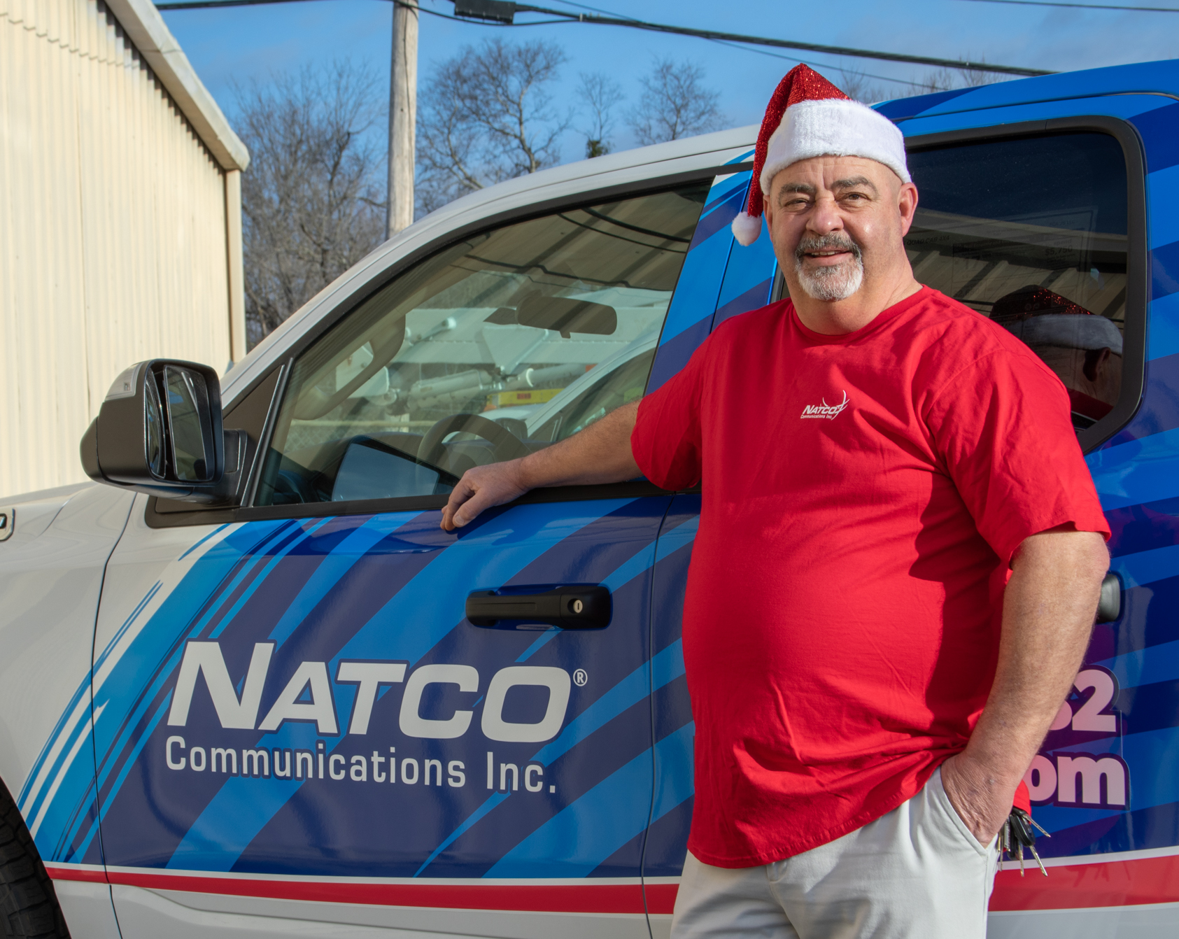 NATCO Director of Customer Care Tim McEuen stands next to a NATCO truck in a Santa hat