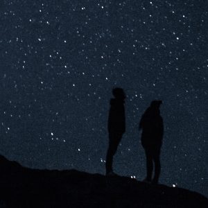 Silhouette of two people in front of a starry sky